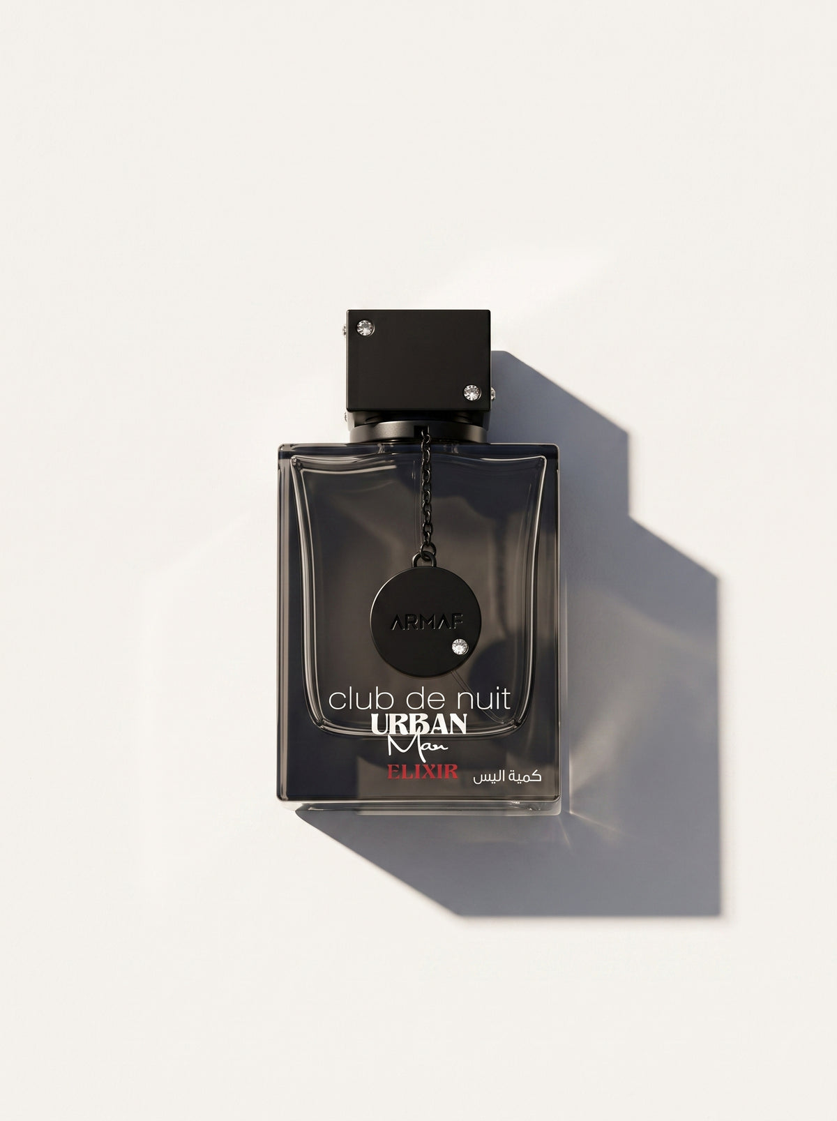 Club de Nuit Urban Man Elixir — smoke-black bottle with a chained tag and red URBAN lettering, top-down