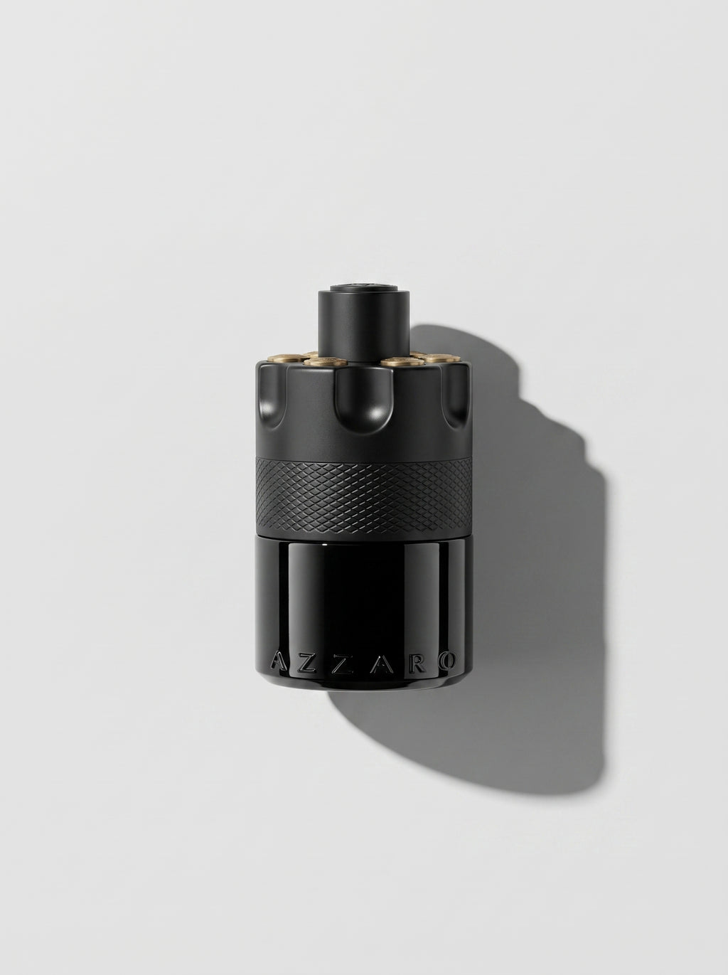 Azzaro Most Wanted — matte black cylinder with a knurled band and gold-topped studs, top-down