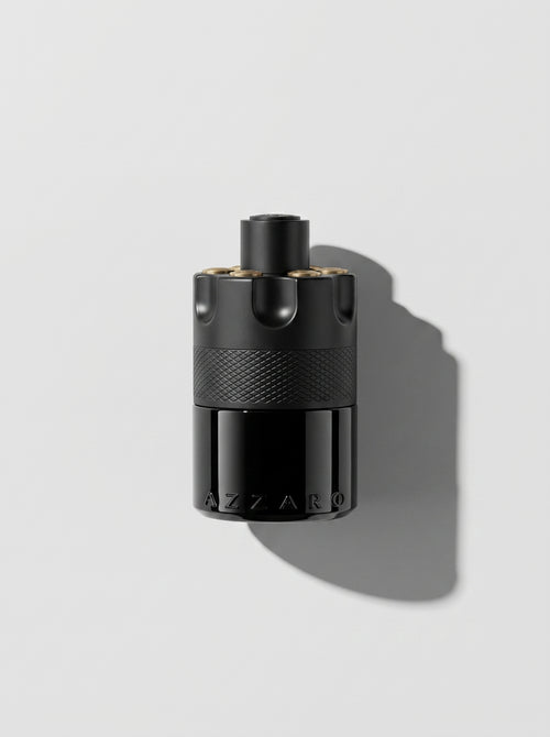 Azzaro Most Wanted — matte black cylinder with a knurled band and gold-topped studs, top-down
