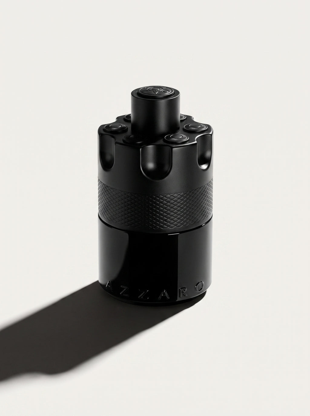 Azzaro Most Wanted — the black studded cylinder upright at eye level, knurled band and AZZARO embossing in view