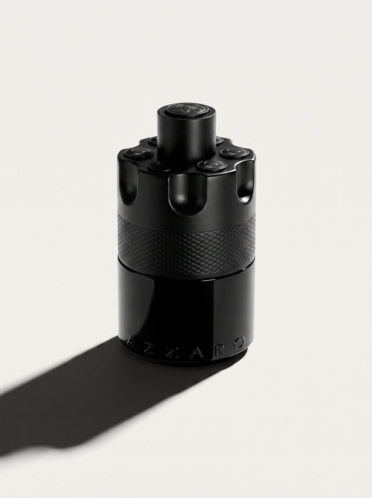 Azzaro Most Wanted — the black studded cylinder upright at eye level, knurled band and AZZARO embossing in view