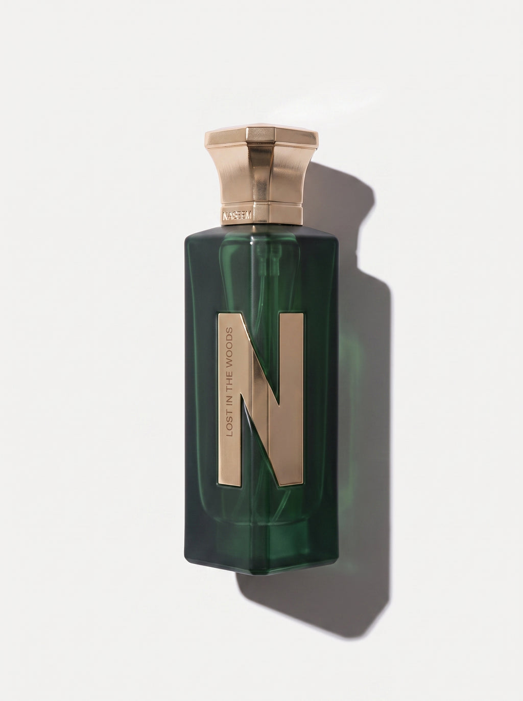 Naseem Lost In The Woods — deep green glass bottle with a rose-gold cap and a large gold N, top-down