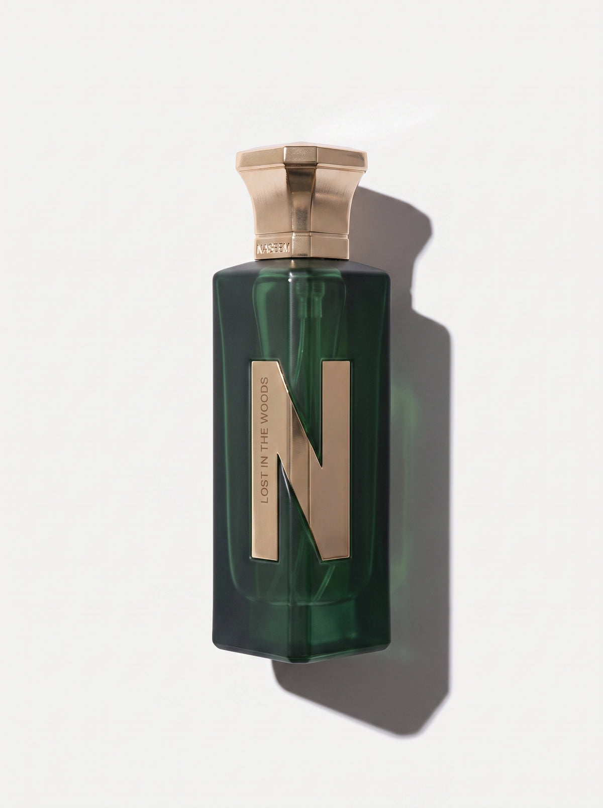 Naseem Lost In The Woods — deep green glass bottle with a rose-gold cap and a large gold N, top-down
