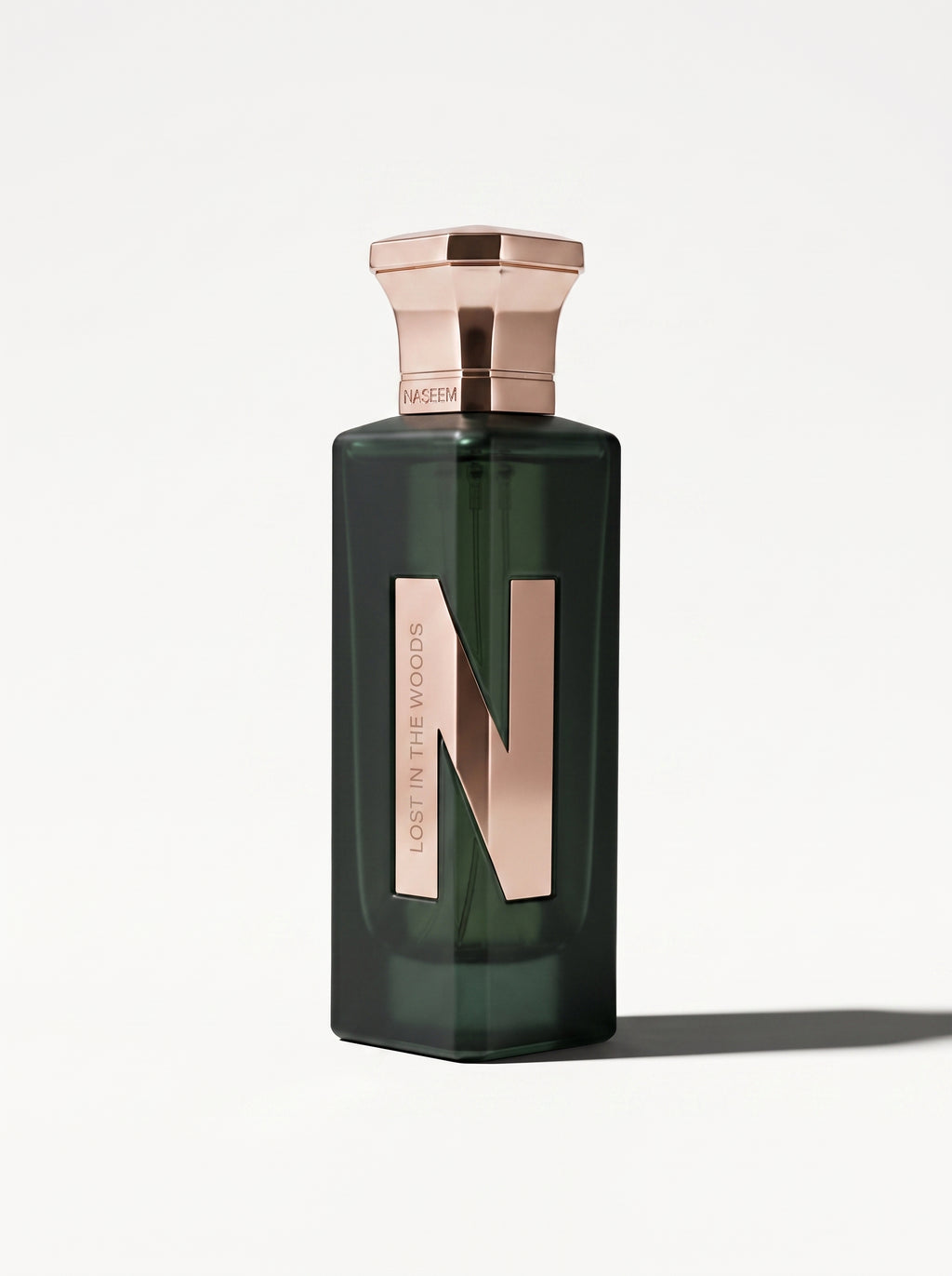 Naseem Lost In The Woods — the green bottle upright at eye level, rose-gold cap and gold N panel in view